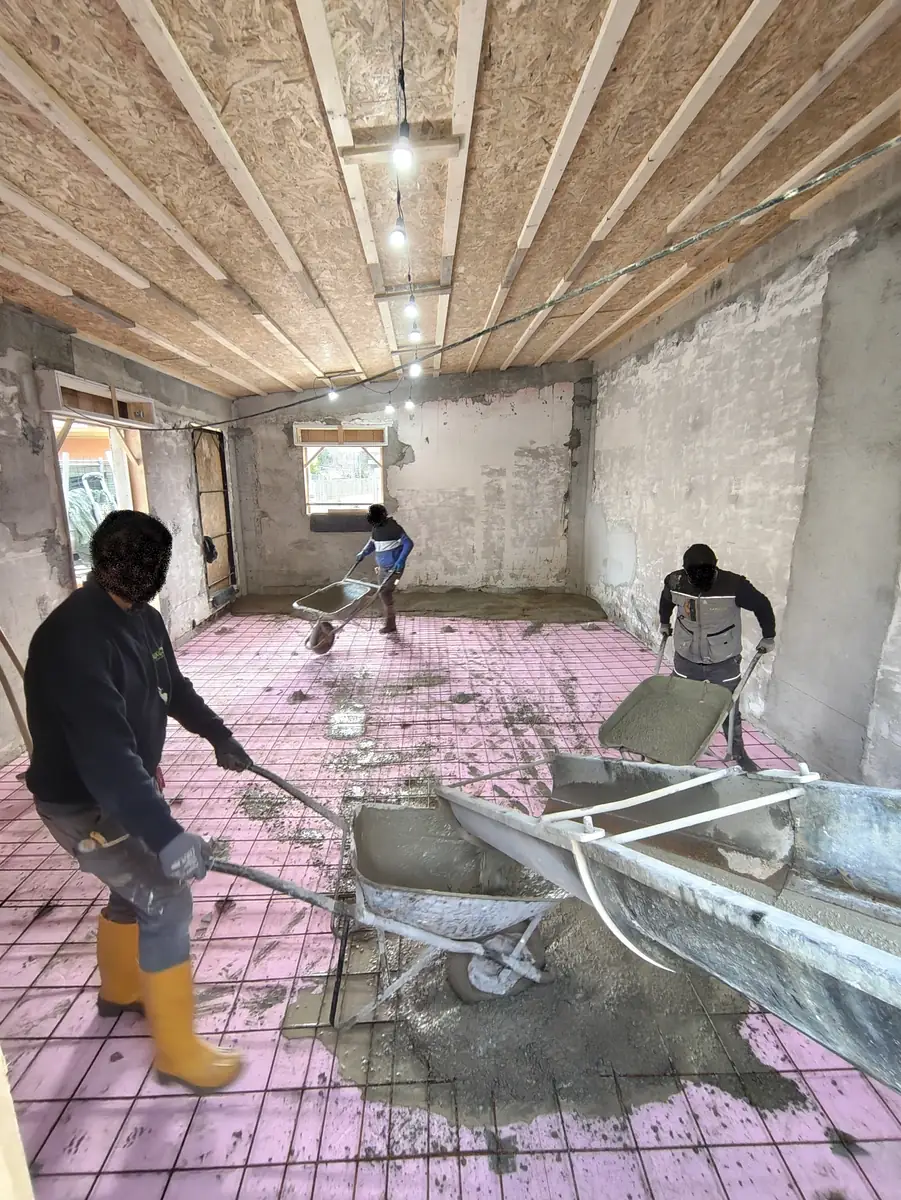 Operai al lavoro sul getto del massetto in un'abitazione